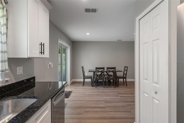 604 Kinnear Dr, Brooksville, FL 34601 - kitchen with light wood finished floors, white cabinets, recessed lighting, dark stone counters, and baseboards