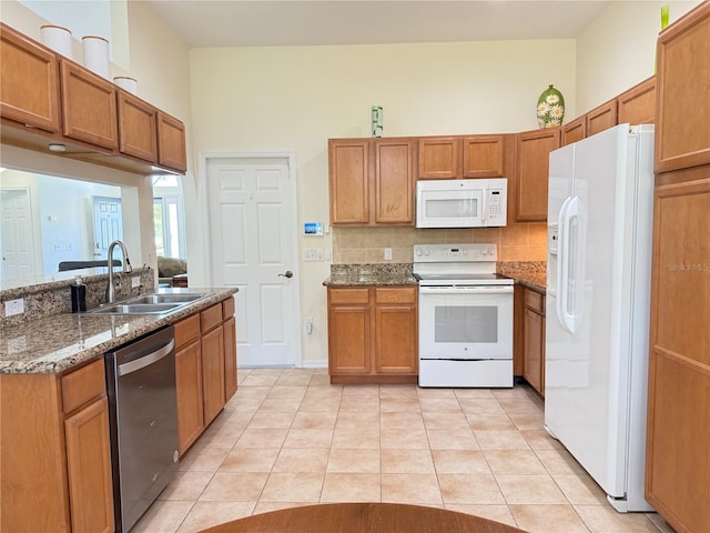 9348 Villa Entrada, New Port Richey, FL 34655 - kitchen with light tile patterned floors, a sink, white appliances, brown cabinetry, and dark stone counters