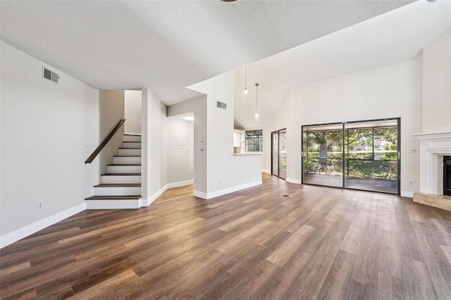 unfurnished living room with a fireplace with raised hearth, wood finished floors, and visible vents