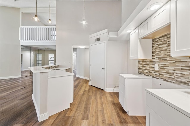 kitchen with decorative backsplash, baseboards, a sink, and high vaulted ceiling
