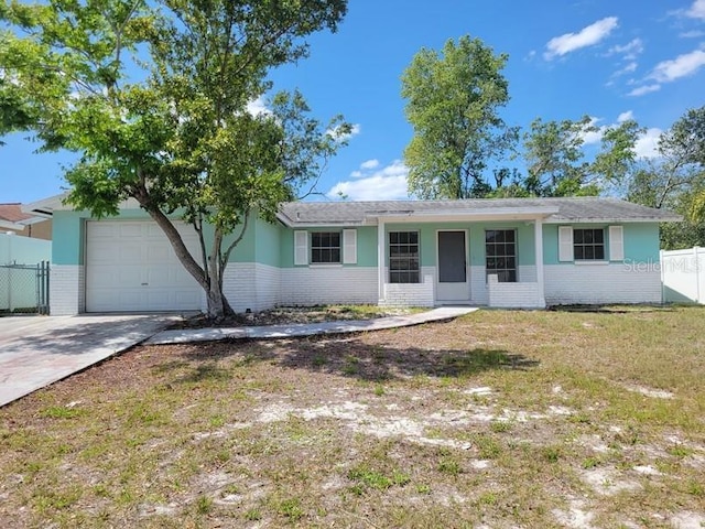 ranch-style home featuring fence, an attached garage, concrete driveway, a front yard, and brick siding