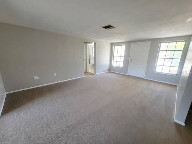carpeted empty room featuring baseboards and visible vents