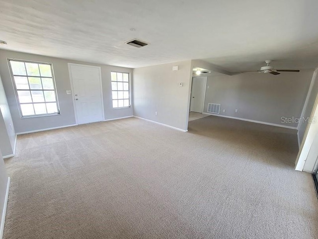 carpeted empty room with baseboards, ceiling fan, and visible vents