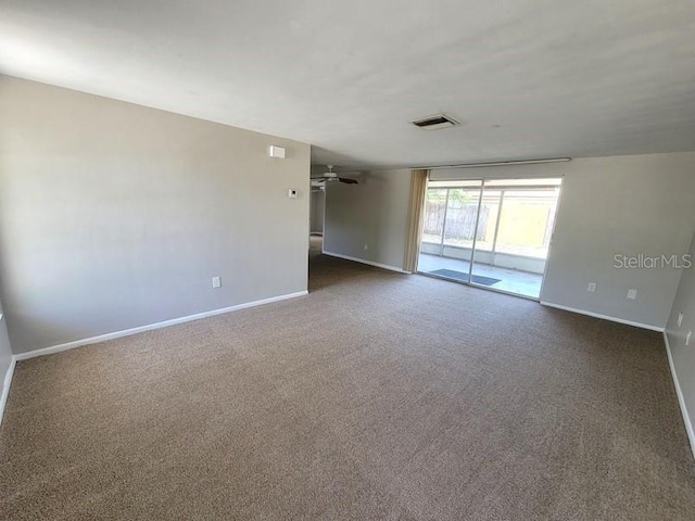 carpeted empty room featuring baseboards, visible vents, and a ceiling fan