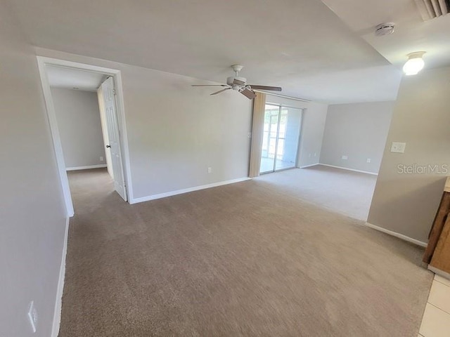 unfurnished room with a ceiling fan, light carpet, and baseboards