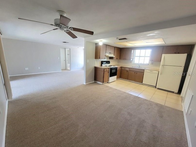 kitchen featuring light tile patterned flooring, light countertops, light carpet, under cabinet range hood, and white appliances