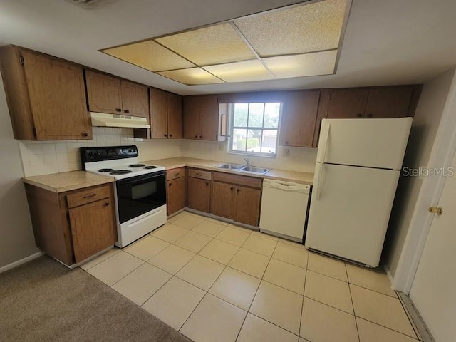kitchen featuring white appliances, light countertops, under cabinet range hood, and a sink