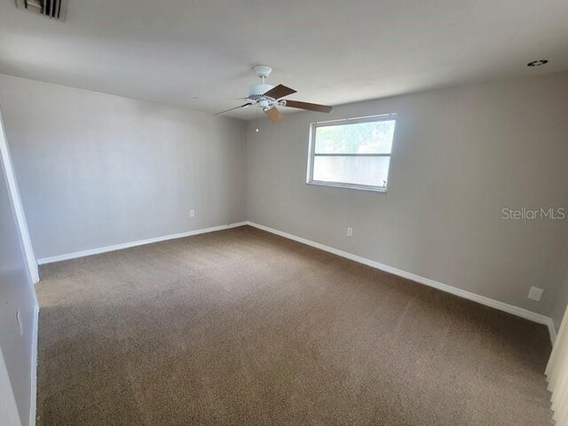 spare room featuring baseboards, carpet floors, ceiling fan, and visible vents