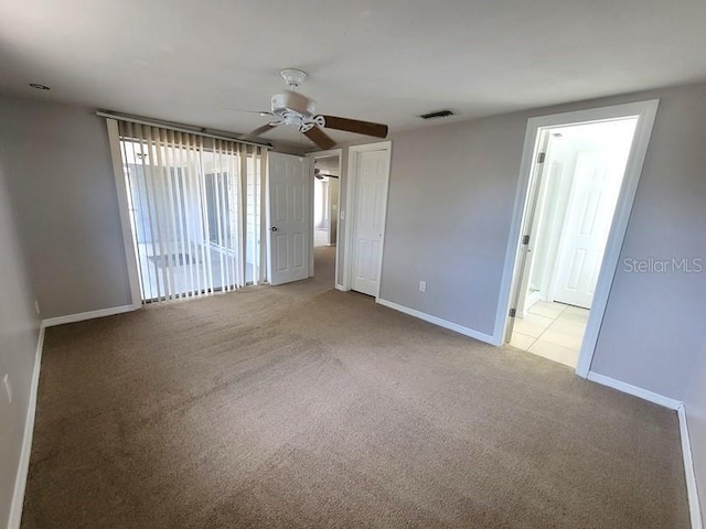 carpeted spare room featuring a ceiling fan, baseboards, and visible vents