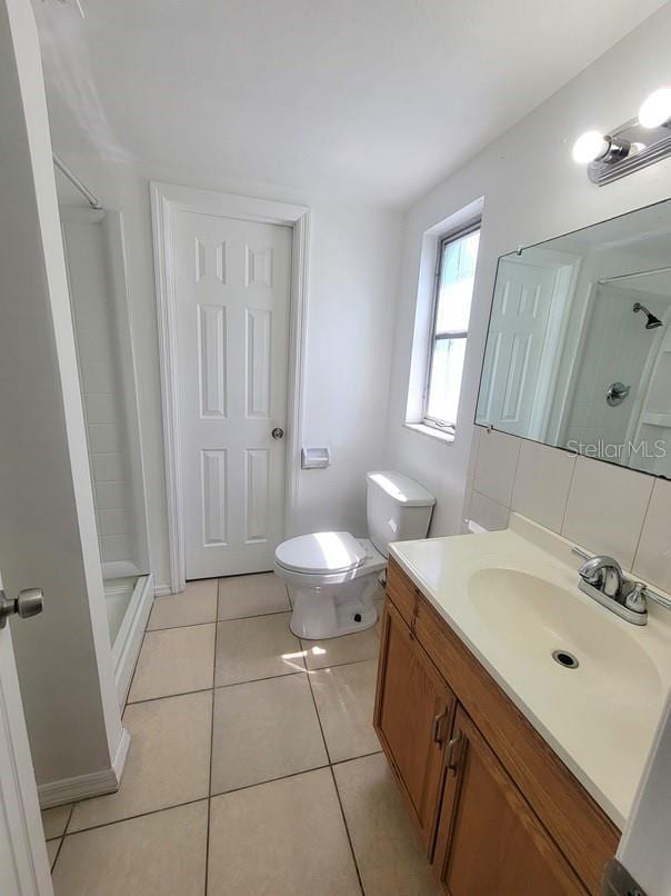 bathroom with vanity, tasteful backsplash, toilet, tile patterned floors, and a stall shower