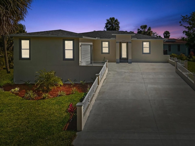 view of front of property featuring a lawn, stucco siding, fence, and roof with shingles