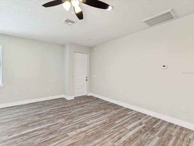 unfurnished room featuring a textured ceiling, visible vents, a ceiling fan, and wood finished floors