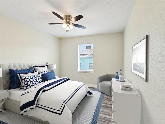 bedroom featuring a textured wall, a textured ceiling, wood finished floors, and a ceiling fan