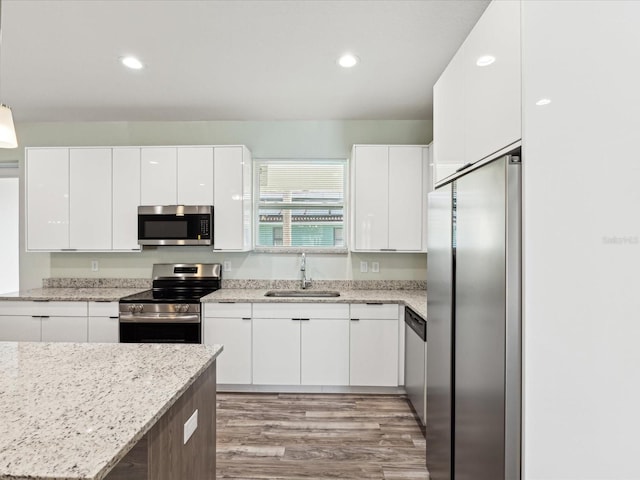 kitchen featuring a sink, light wood-style floors, white cabinets, modern cabinets, and appliances with stainless steel finishes