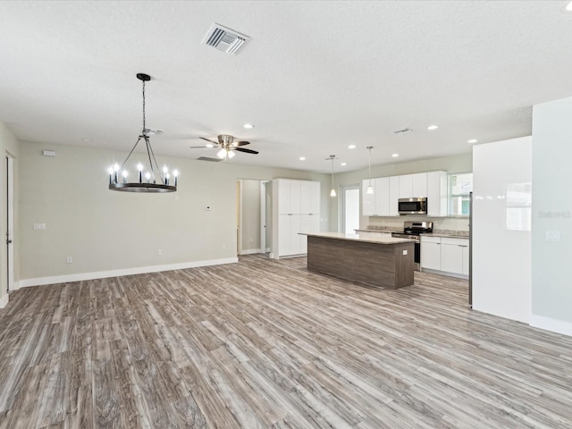 kitchen featuring light countertops, a center island, open floor plan, stainless steel appliances, and visible vents
