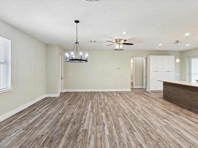 unfurnished living room featuring a textured ceiling, baseboards, light wood finished floors, and visible vents