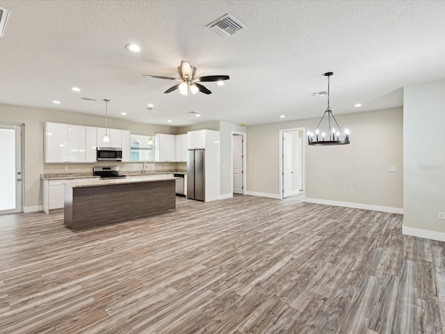 kitchen featuring white cabinets, stainless steel appliances, a center island, and visible vents