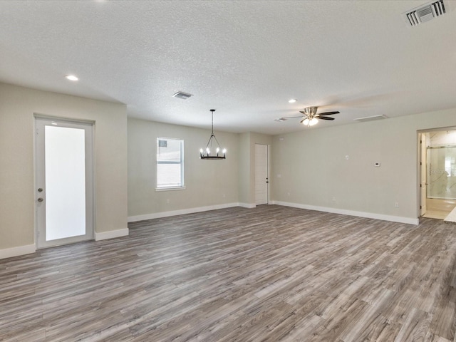 unfurnished living room with baseboards, visible vents, wood finished floors, and a textured ceiling