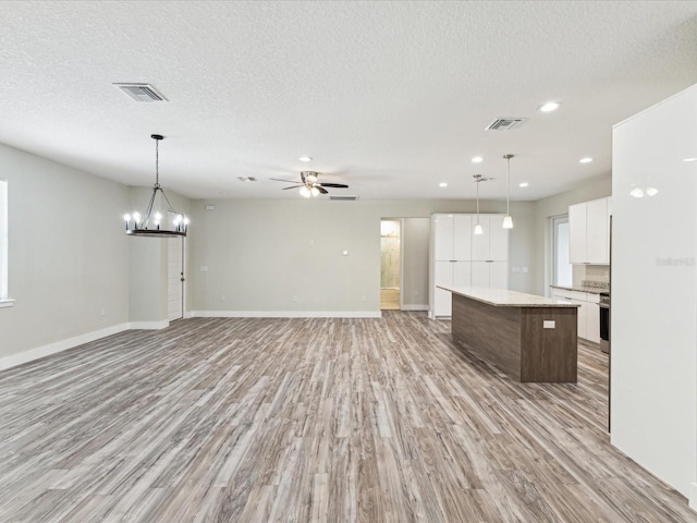 kitchen with open floor plan, a kitchen island, white cabinetry, and visible vents