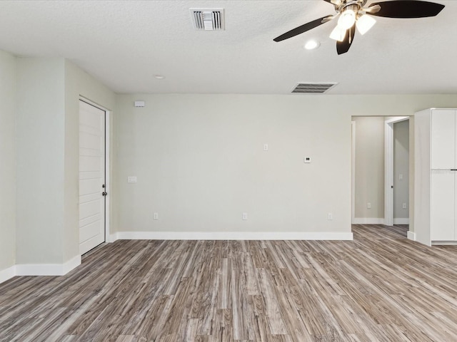 spare room featuring baseboards, visible vents, wood finished floors, and a ceiling fan