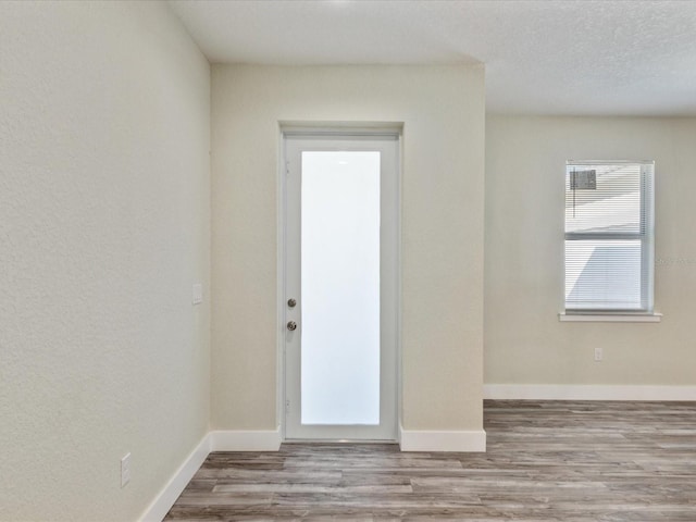 spare room with baseboards, wood finished floors, and a textured ceiling