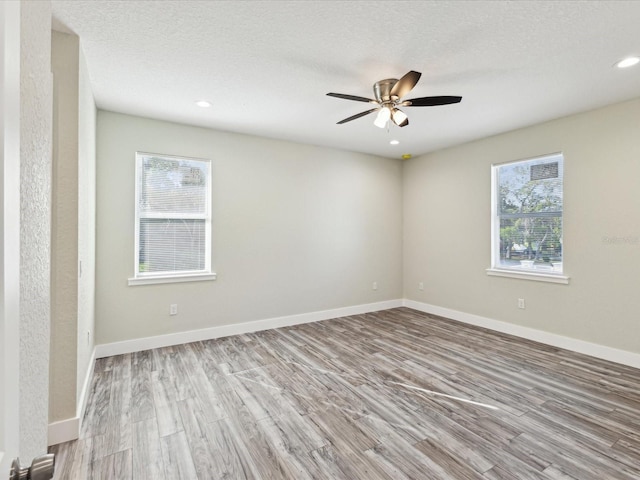 unfurnished room featuring a textured ceiling, baseboards, wood finished floors, recessed lighting, and a ceiling fan