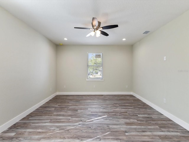 empty room with baseboards, ceiling fan, visible vents, and wood finished floors