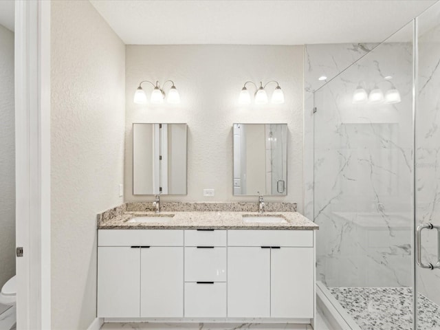 full bath featuring double vanity, toilet, a sink, and a marble finish shower