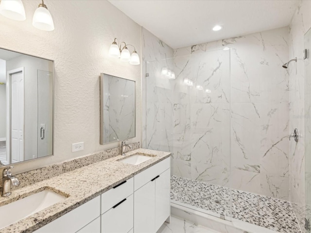 full bath with marble finish floor, a sink, a marble finish shower, and double vanity