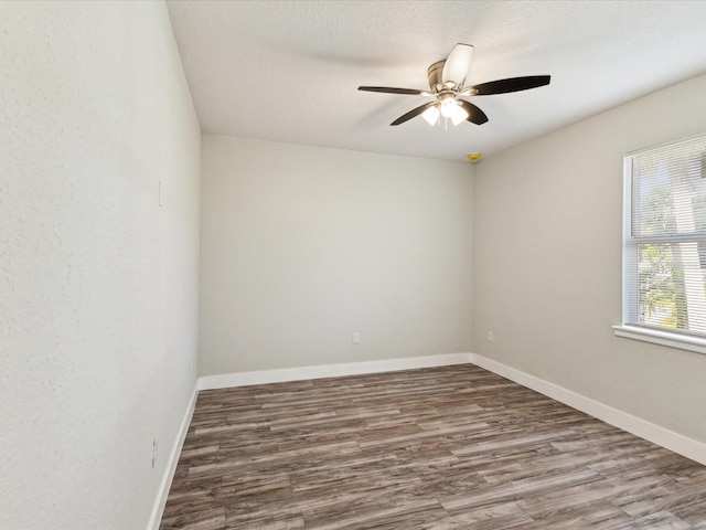 spare room with a textured ceiling, baseboards, wood finished floors, and a ceiling fan