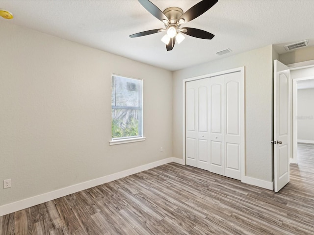 unfurnished bedroom featuring baseboards, visible vents, and wood finished floors