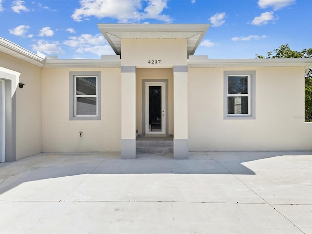 entrance to property featuring stucco siding and a patio area