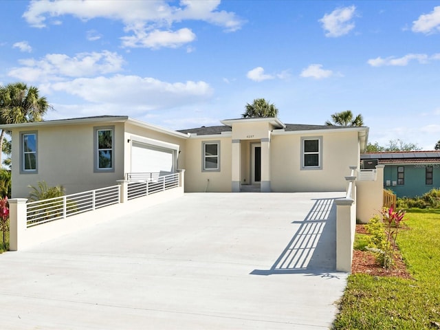 view of front of home featuring fence, driveway, stucco siding, and a garage