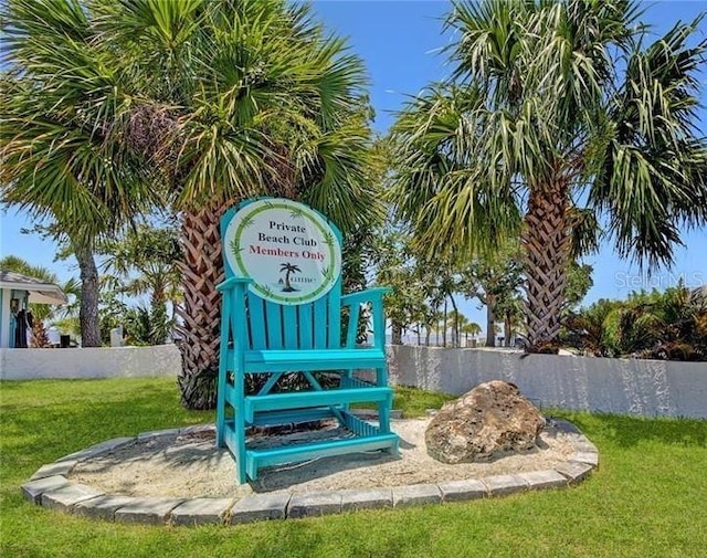 community / neighborhood sign featuring fence and a lawn