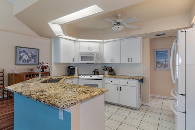 kitchen with white appliances, a sink, a peninsula, decorative backsplash, and ceiling fan