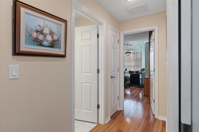corridor with light wood-style floors, a desk, and baseboards