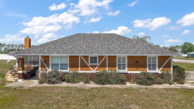 view of front facade with stucco siding, a chimney, and a front yard