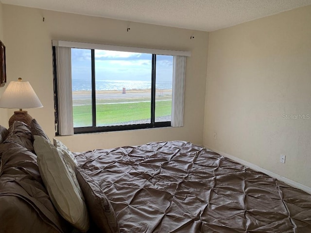 2600 Ocean Shore Blvd Unit 111, Ormond Beach, FL 32176 - bedroom featuring a water view and a textured ceiling