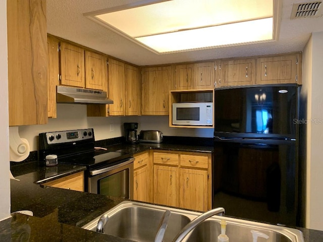 2600 Ocean Shore Blvd Unit 111, Ormond Beach, FL 32176 - kitchen with stainless steel electric range oven, white microwave, under cabinet range hood, freestanding refrigerator, and dark stone countertops