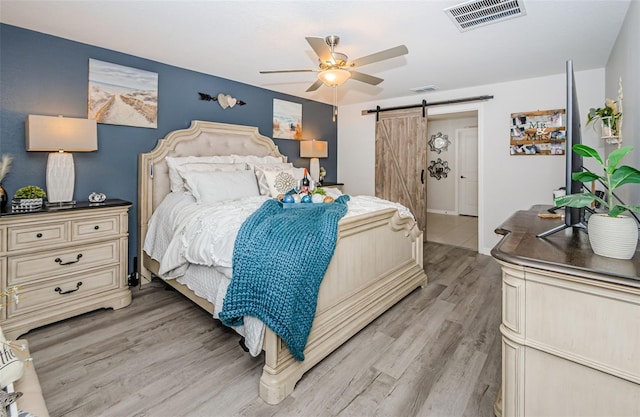 36419 Flats St, Zephyrhills, FL 33541 - bedroom featuring a barn door, light wood-style flooring, and a ceiling fan