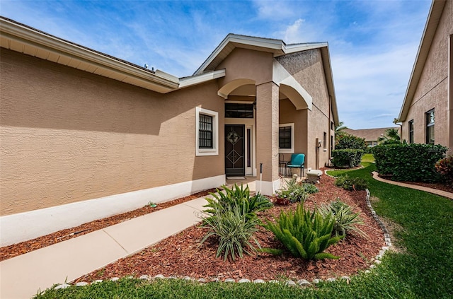 9636 Brookdale Dr, New Port Richey, FL 34655 - view of exterior entry with stucco siding and a yard