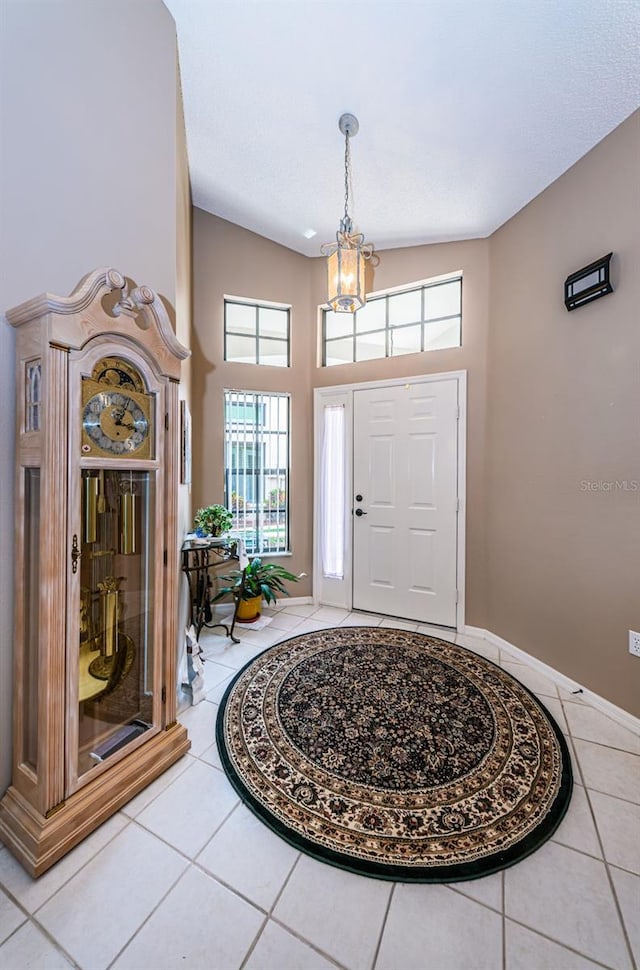 9636 Brookdale Dr, New Port Richey, FL 34655 - tiled foyer entrance with baseboards, a towering ceiling, a healthy amount of sunlight, and a notable chandelier