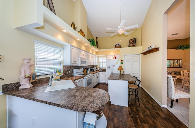9636 Brookdale Dr, New Port Richey, FL 34655 - kitchen with white appliances, a breakfast bar, dark countertops, a ceiling fan, and a sink