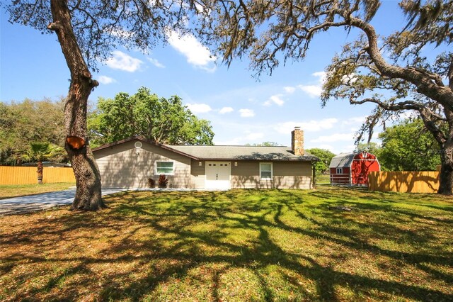 back of house with a chimney, fence, an outdoor structure, and a yard