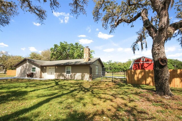 view of side of property with a chimney, an outbuilding, fence, a storage shed, and a lawn