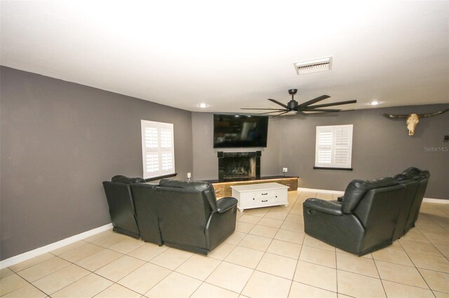 living area with visible vents, baseboards, a fireplace, ceiling fan, and light tile patterned floors