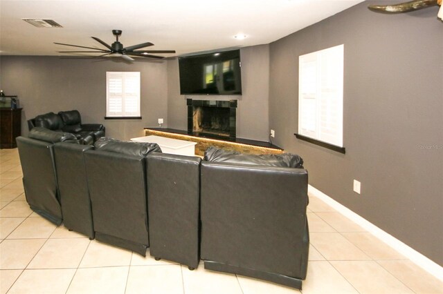 living room featuring baseboards, light tile patterned flooring, visible vents, a ceiling fan, and a fireplace