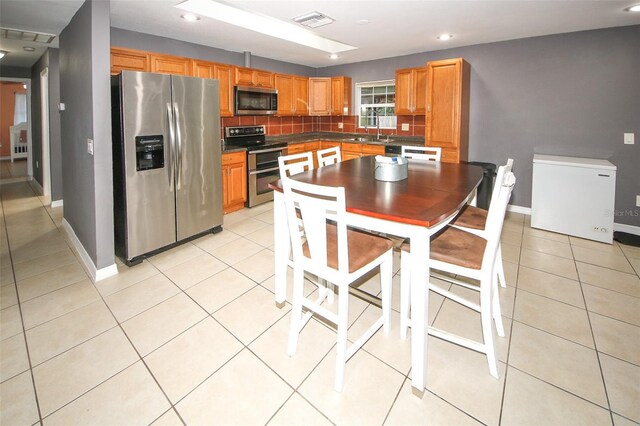 kitchen featuring light tile patterned flooring, tasteful backsplash, appliances with stainless steel finishes, baseboards, and visible vents