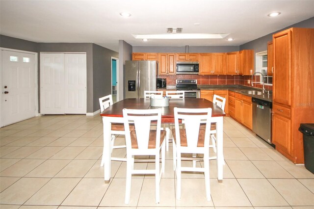 kitchen featuring light tile patterned flooring, visible vents, stainless steel appliances, tasteful backsplash, and a sink