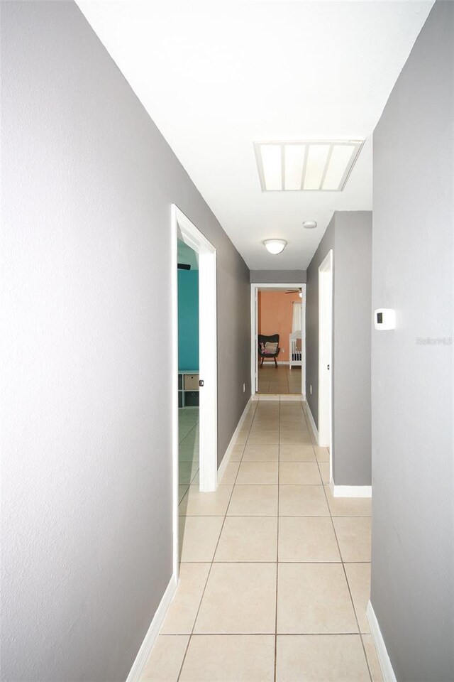 hallway featuring baseboards and light tile patterned floors
